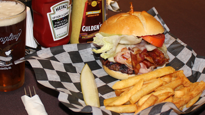 The Bunker Buster. A gourmet burger sandwich: a burger topped with barbeque sauce, cheese, ham, bacon, lettuce and tomato.